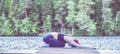 Young attractive girl practicing yoga, sitting in Child exercise, Balasana pose on the lake. The concept of appeasement, healthy