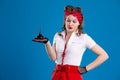 An attractive girl with a red bandana on her head holds a bottle of perfume with a surprised look on her face. Royalty Free Stock Photo