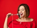 Attractive girl in red dress holding a fork in hands. on the headphone plug. prepared to eat Royalty Free Stock Photo