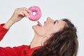 Attractive girl in a red dress licks a doughnut