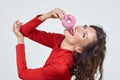 Attractive girl in a red dress licks a doughnut