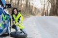 attractive girl remove wheel from car at road alone