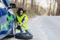 attractive girl remove wheel from car at road alone