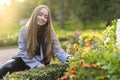 Attractive girl smiling young woman in autumn park with dahlia flowers on flower bed on sunny day Royalty Free Stock Photo