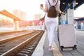 Attractive girl is standing with luggage at the station and waiting for the train, the student is going on a trip, she is walking Royalty Free Stock Photo