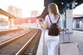 Attractive girl is standing with luggage at the station and waiting for the train, the student is going on a trip, she is walking Royalty Free Stock Photo