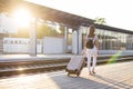 Attractive girl is standing with luggage at the station and waiting for the train, the student is going on a trip, she is walking Royalty Free Stock Photo
