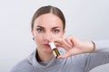 Attractive girl taking a medicine with spray inside the nose on light background Royalty Free Stock Photo