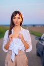 Attractive girl in white shirt posing near car on country road in sunset Royalty Free Stock Photo