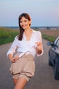 Attractive girl in white shirt posing near car on country road in sunset Royalty Free Stock Photo