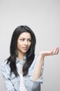 Attractive girl woman with long black hair palms up showing something over a grey background. Royalty Free Stock Photo