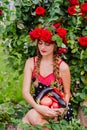 Attractive girl with a wreath of red roses with a basket of vegetables: tomatoes, eggplants, peppers Royalty Free Stock Photo