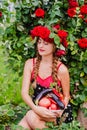 Attractive girl with a wreath of red roses with a basket of vegetables: tomatoes, eggplants, peppers Royalty Free Stock Photo