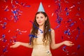 Girl in a yellow T-shirt and in a festive cap throws blue and silver confetti. Royalty Free Stock Photo