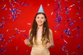 Girl in a yellow T-shirt and in a festive cap throws blue and silver confetti. Royalty Free Stock Photo