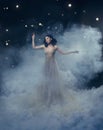 An attractive goddess stands in the clouds in a luxurious, gold, sparkling dress. Whimsical hairstyle. Against the