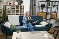 Attractive grey-haired woman presenting financial report to colleagues through video call on laptop Royalty Free Stock Photo