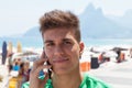 Attractive guy in a green shirt at beach speaking at phone Royalty Free Stock Photo