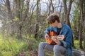 An attractive guy plays the guitar in a forest