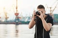 Attractive guy working with camera. Young stylish photographer looking through camera during photo session with gorgeous