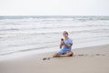 Attractive and handsome man on his 30s sitting on the sand relaxed on the beach laughing in front of the sea texting on mobile pho Royalty Free Stock Photo