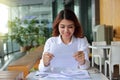 Attractive happy Asian business woman smiling with document paper in her office background. Royalty Free Stock Photo