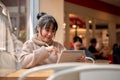 An attractive, happy Asian female is working remotely at a cafe co-working space, using her tablet Royalty Free Stock Photo