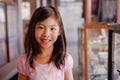 An attractive happy Asian girl with long hair smiling brightly at an antique shop with blur background