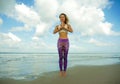 Attractive and happy athletic girl at beautiful beach in yoga pose concentrated and relaxed doing meditation exercise outdoors in Royalty Free Stock Photo