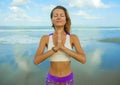 Attractive and happy athletic girl at beautiful beach in yoga pose concentrated and relaxed doing meditation exercise outdoors in Royalty Free Stock Photo