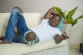 Attractive and happy black African American man relaxed at home sofa couch enjoying watching television sports or movie smiling Royalty Free Stock Photo