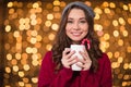 Attractive happy curly young woman drinking coffee with candy cane