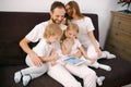 Attractive happy, family consisted of mother, father, son and daughter sitting on sofa at home with tablet Royalty Free Stock Photo