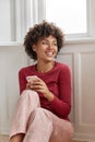 Attractive happy female model with Afro hairstyle, wears nightclothes, reads pleasant text message, smiles positively Royalty Free Stock Photo