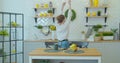 Attractive happy girl dancing and singing in kitchen while using smartphone and listening to music at home in the Royalty Free Stock Photo