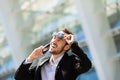 Attractive happy man talking on cell phone, raised his glasses in surprise Royalty Free Stock Photo