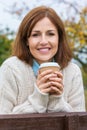 Attractive Happy Middle Aged Woman Resting on Fence With Coffee Royalty Free Stock Photo