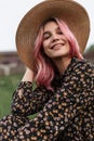 Attractive happy pretty young woman portrait with lovely smile in straw fashion hat in black elegant floral dress sitting outdoors