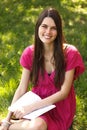 Attractive happy smiling student teen girl reading book in park Royalty Free Stock Photo