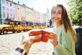 Attractive happy smiling woman sitting in the center of old city with paper cup of coffee