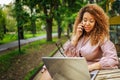 Attractive happy stylish plus size African American Black business woman speaks phone working online on laptop computer Royalty Free Stock Photo