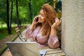 Attractive happy stylish plus size African American Black business woman speaks phone working online on laptop computer Royalty Free Stock Photo