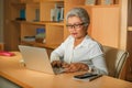 Attractive and happy successful mature Asian woman working relaxed  at laptop computer desk smiling confident in business and Royalty Free Stock Photo