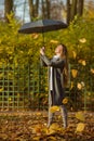 Attractive happy woman in a gray coat holds an umbrella in her hands.