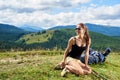 Woman hiker hiking on grassy hill, wearing backpack, using trekking sticks in the mountains Royalty Free Stock Photo