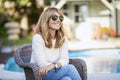 Attractive and happy woman wearing sunglasses and casual clothes while relaxing at the backyard at home Royalty Free Stock Photo