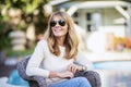 Attractive and happy woman wearing sunglasses and casual clothes while relaxing at the backyard at home Royalty Free Stock Photo