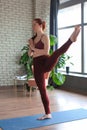 Attractive happy woman working out indoors, doing yoga exercise, variation of Natarajasana