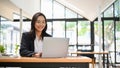 Attractive Asian businesswoman working on her project on laptop in cafe co-working space Royalty Free Stock Photo