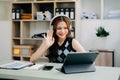 Attractive happy young student studying at the college library, sitting at the desk, using a laptop computer, tablet and Royalty Free Stock Photo